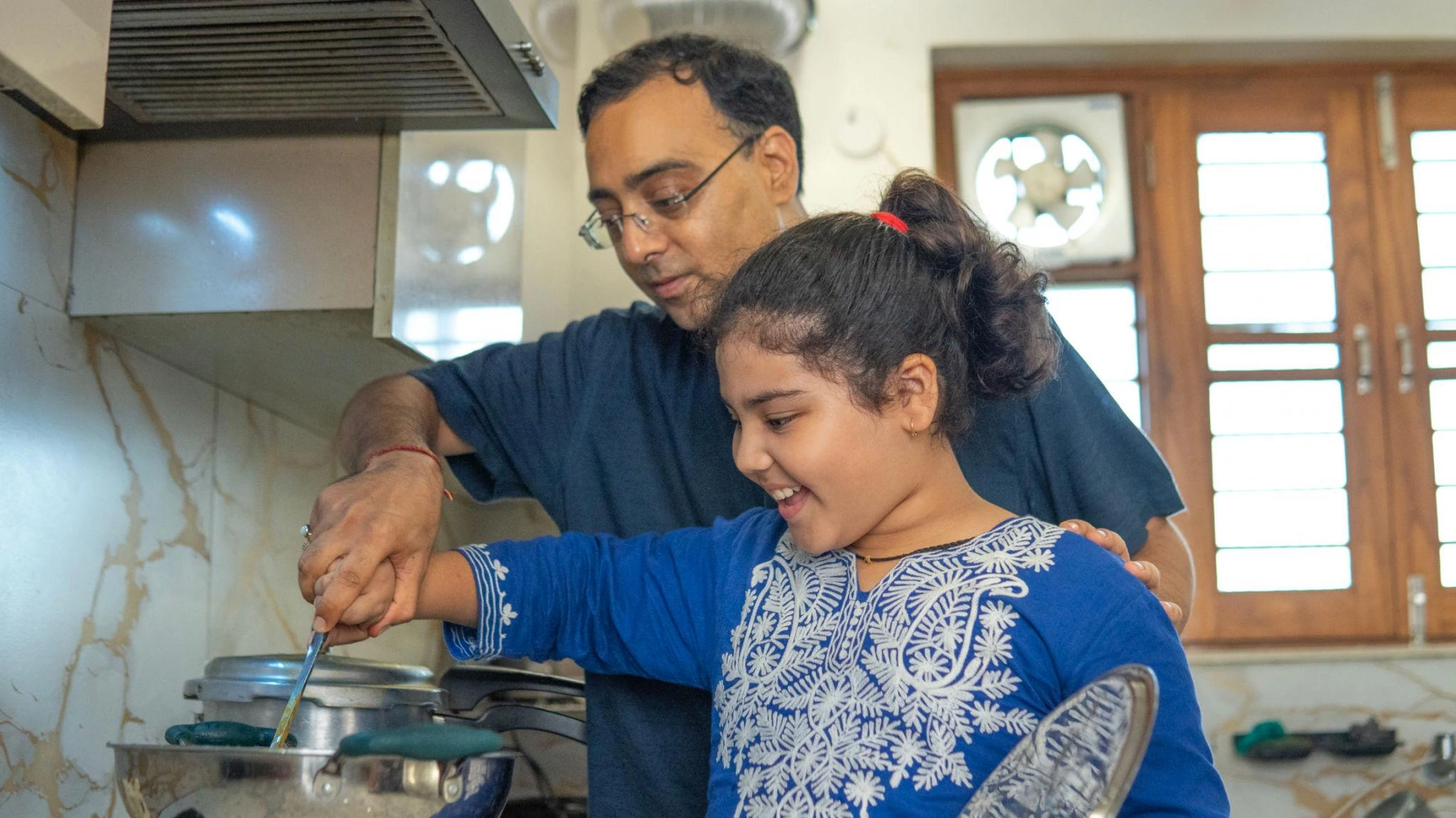 Father and daughter cooking together at the stove